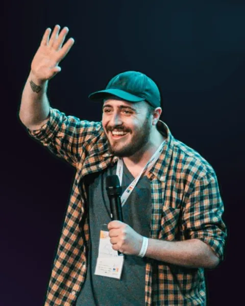 Gherardo sul palco durante un intervento, sorride e saluta il pubblico con il microfono in mano