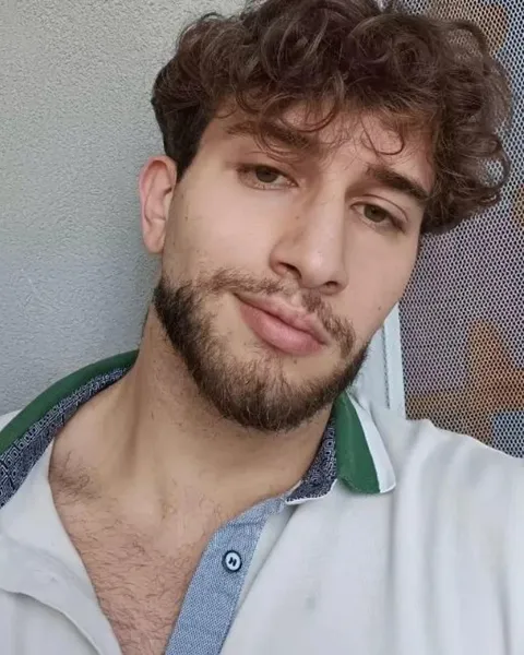 Ritratto di Hafedh, capelli ricci e barba, polo bianca