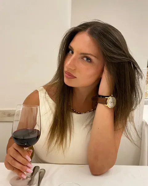 Ritratto di Nicole Cristofaro seduta a un tavolo apparecchiato, con un calice di vino rosso